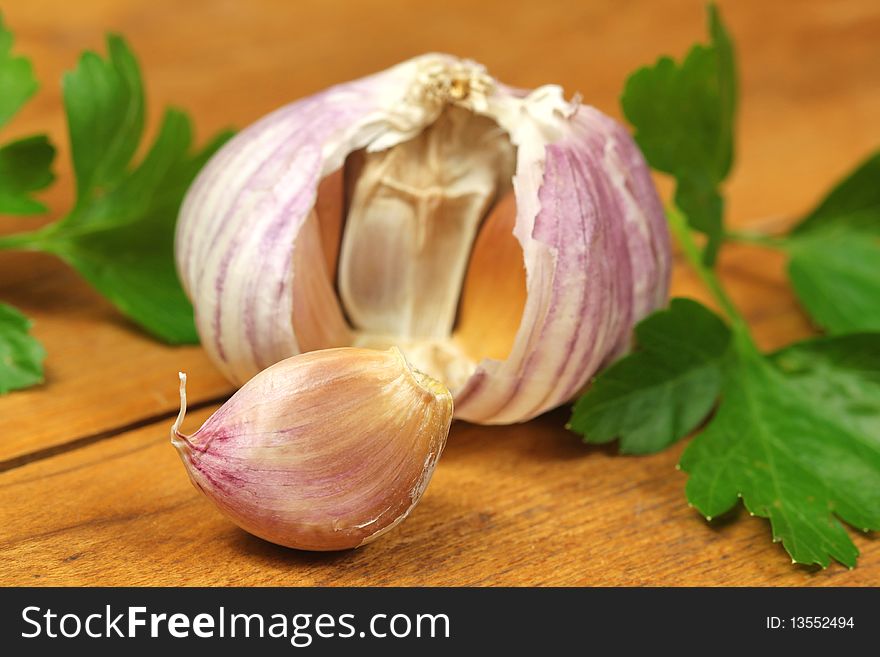 Fresh garlic clove and green parsley on wooden board. Fresh garlic clove and green parsley on wooden board