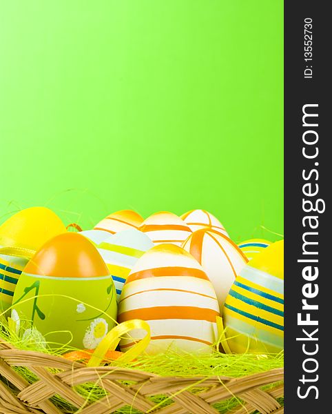Colorful Easter Eggs basket set on green background