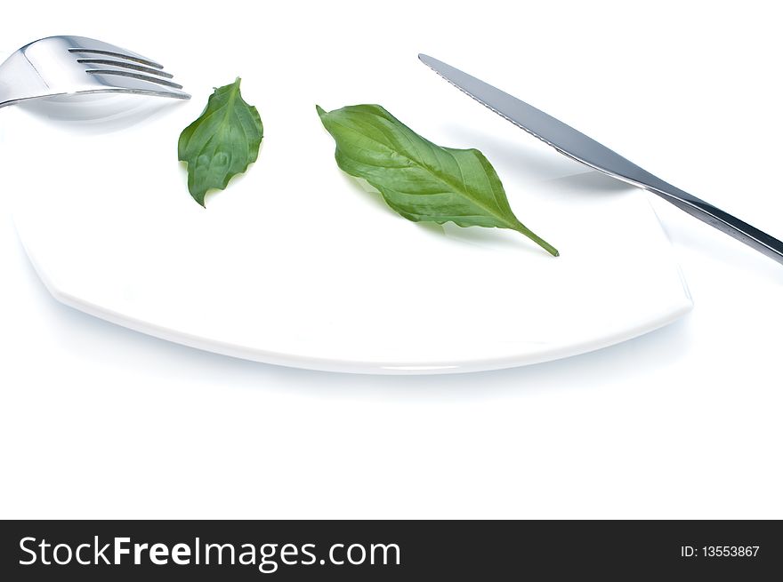 Knife , fork and fresh green leaves on a plate- diet concept. Knife , fork and fresh green leaves on a plate- diet concept