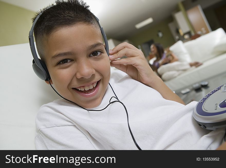 Boy Listening to Music on Portable CD Player in living room, portrait, close up