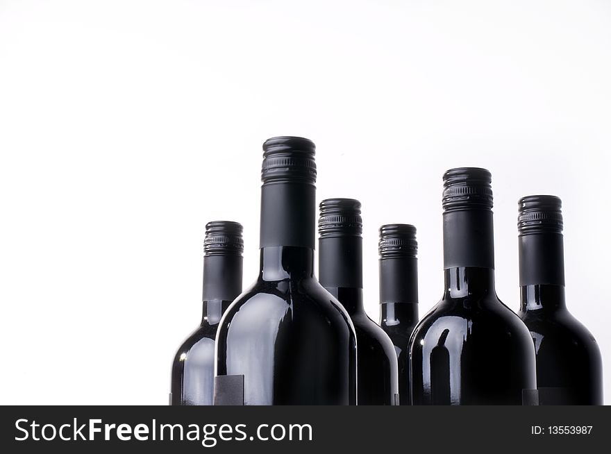 Dark wine bottles in a row against a white background.