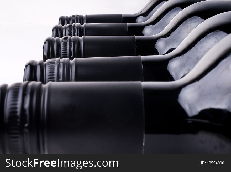 Dark wine bottles in a row against a white background. Dark wine bottles in a row against a white background.