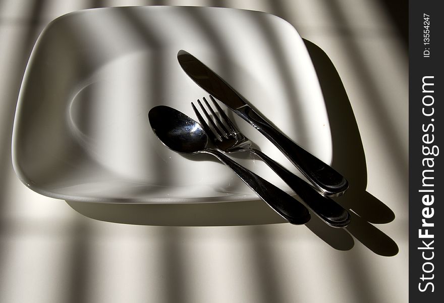 Plate and silverware in the morning sunlight. Plate and silverware in the morning sunlight