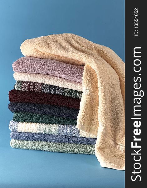 Stack of different colored folded towels sit on a blue background