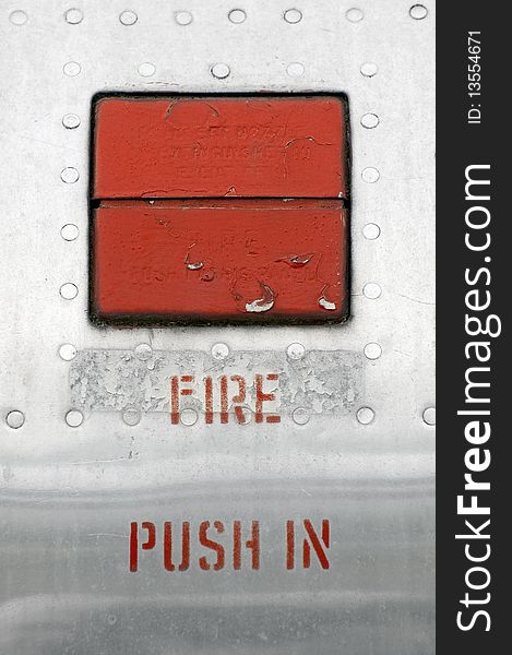 Fire emergency button embedded in an old metal panel. Fire emergency button embedded in an old metal panel