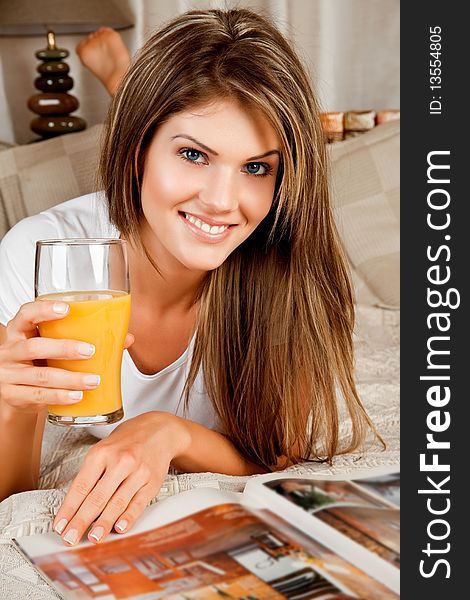 Young beauty woman couch in the bed with a glass of orange juice and a magazine. Young beauty woman couch in the bed with a glass of orange juice and a magazine