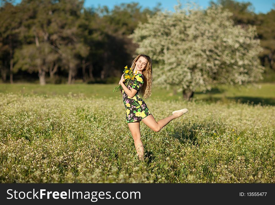 Beautiful young woman jumping in blooming meadow