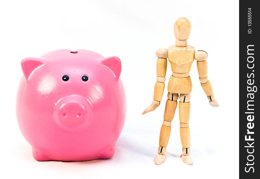 Pink piggy bank and wooden mannequin person stand beside each other on a white background. Pink piggy bank and wooden mannequin person stand beside each other on a white background.