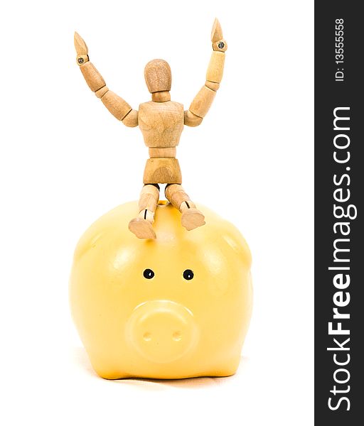 Wood mannequin person sitting atop a yellow piggy bank on a white background celebrating financial successes.