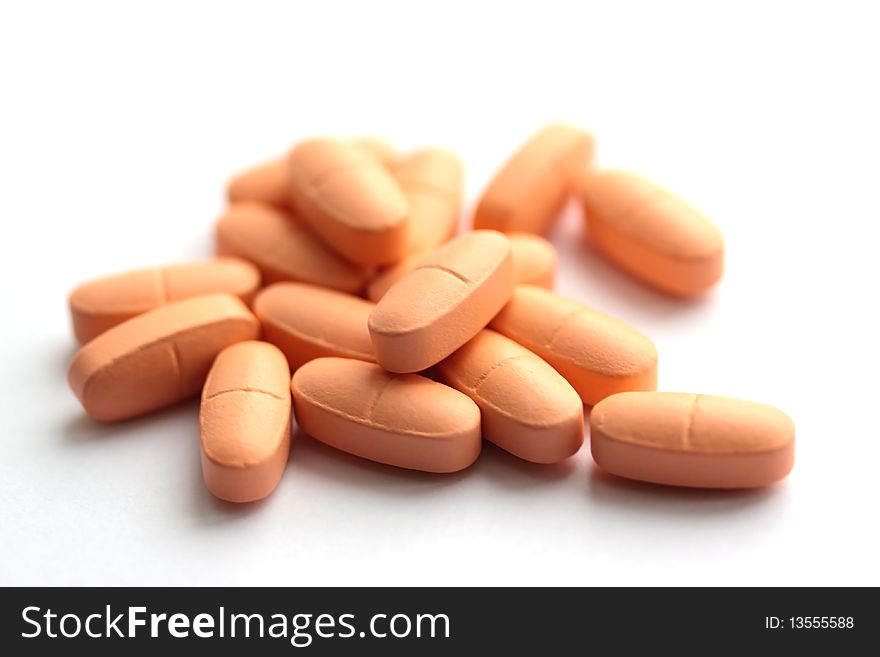 Group of light orange pills on a white background