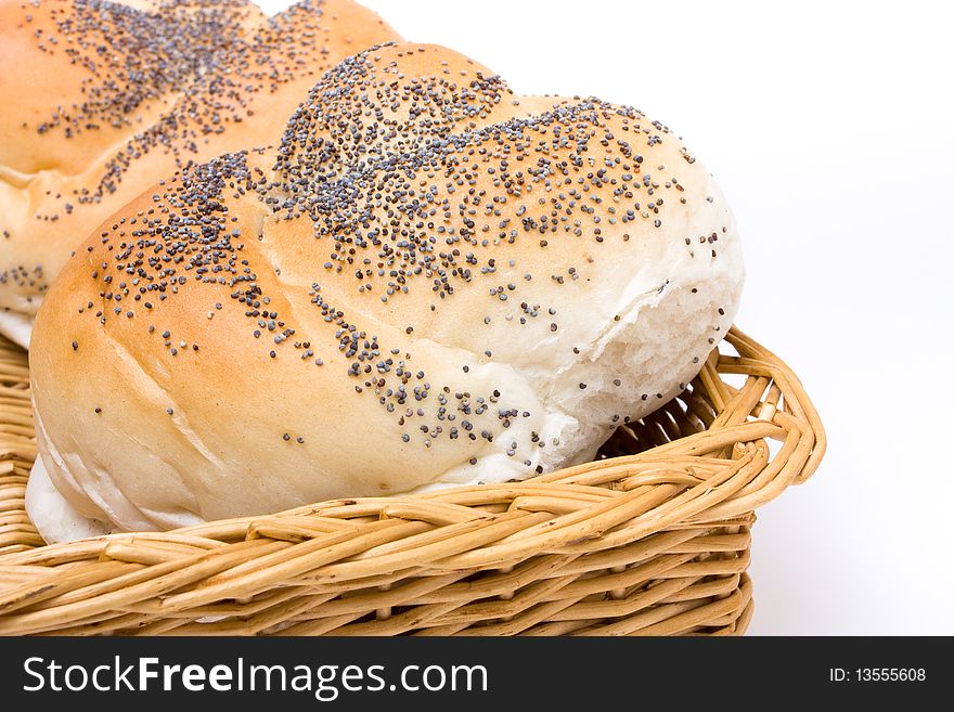 Seeded bread roll in wicker basket from low viewpoint isolated against white background.
