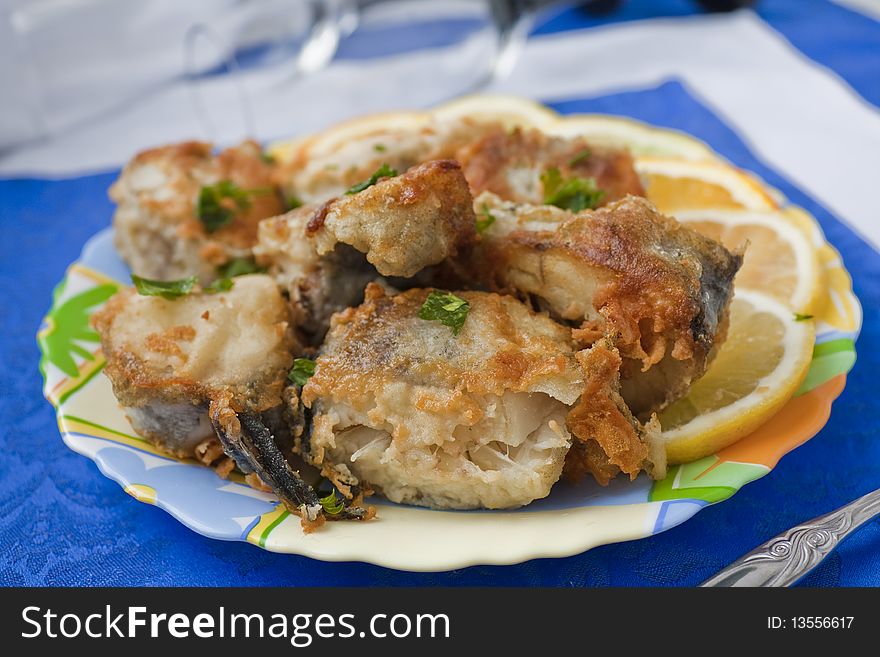 Full plate of the fried pieces of a fish of a pollack on a dark blue napkin