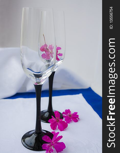 Two empty wine glasses costing on a white cloth in pink flowers