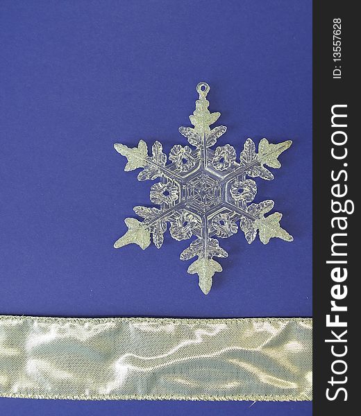 White snowflake and silver ribbon isolated on blue