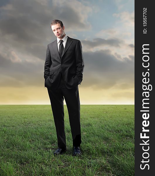 Young businessman standing on a green meadow