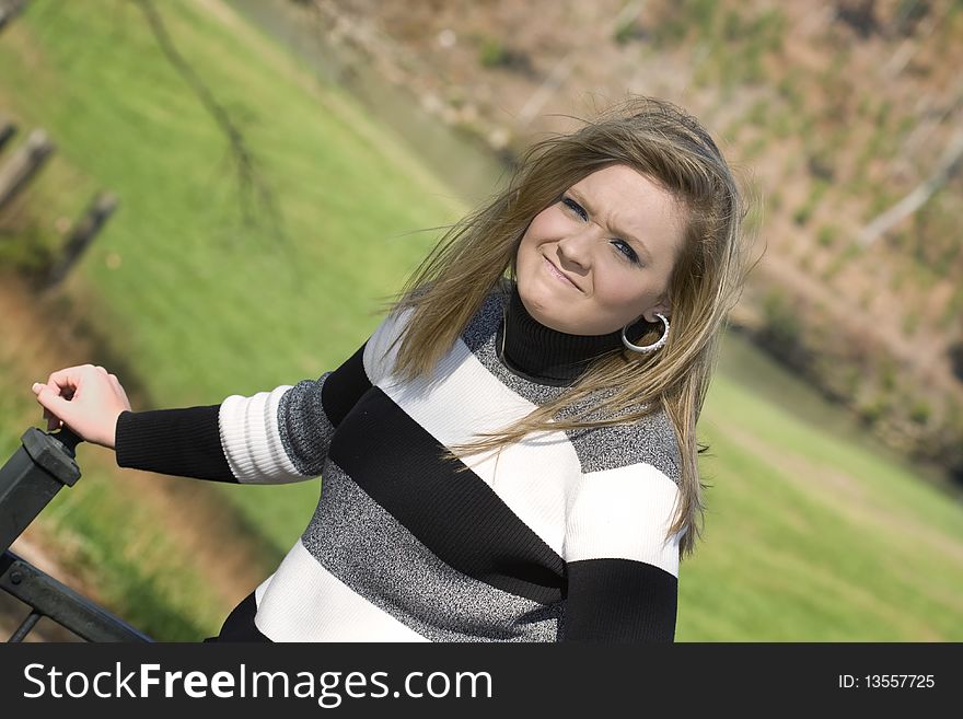 Beautiful young woman frustrated because the wind wont stop blowing her hair. Beautiful young woman frustrated because the wind wont stop blowing her hair