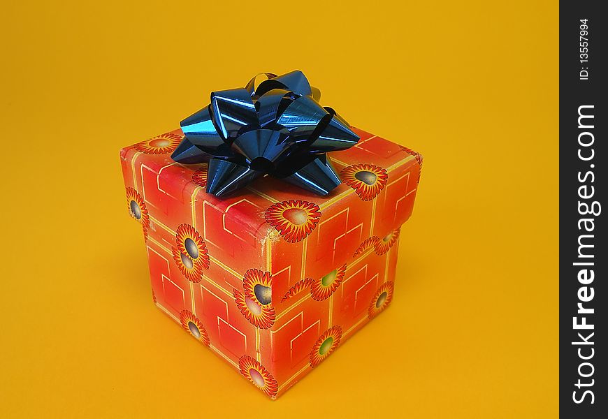 Red gift box with blue ribbon isolated on yellow