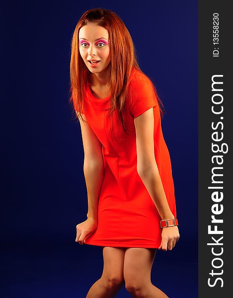 The young girl in a red dress in style fashion on a dark blue background