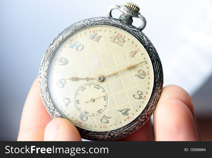 Silver pocket watch on tip of fingers