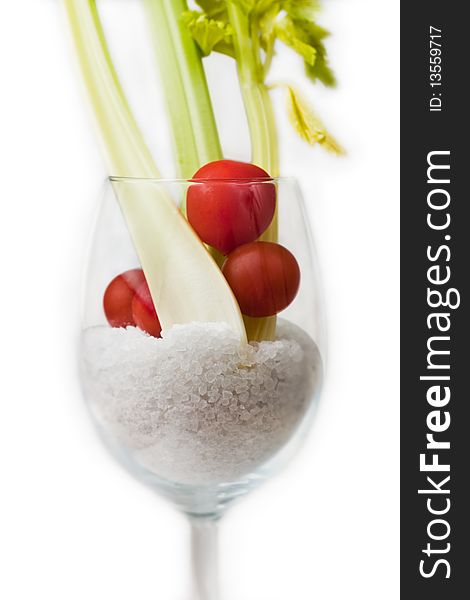 A stylish glass containing fresh celery and tomatoes with salt