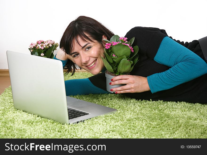 Beautiful woman with flowers and laptop on green rug. Beautiful woman with flowers and laptop on green rug