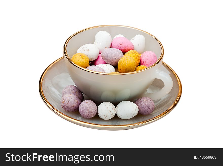 A china tea cup filled with chocolate easter eggs isolated on white
