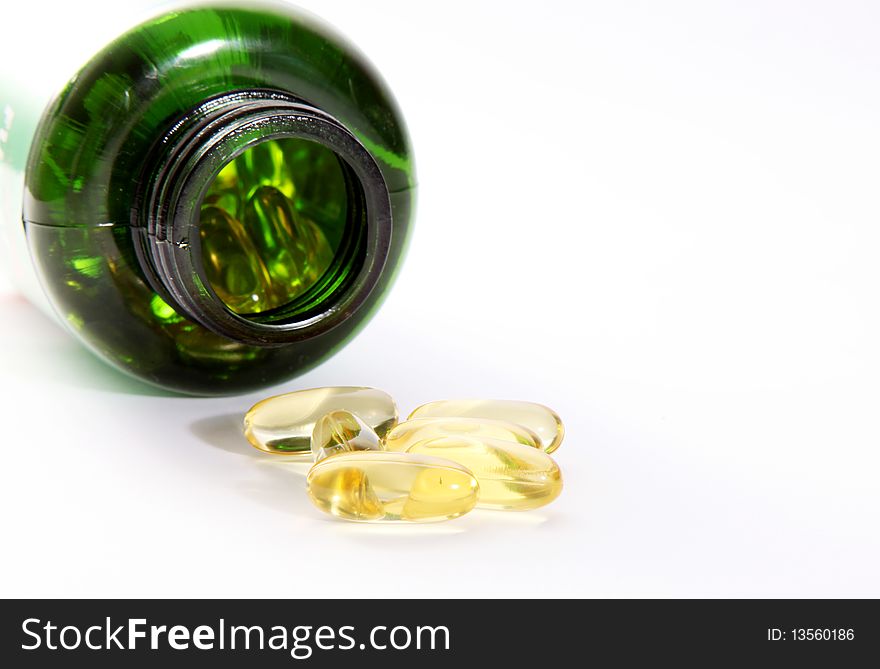 Yellow pills and green bottle on light background. Yellow pills and green bottle on light background