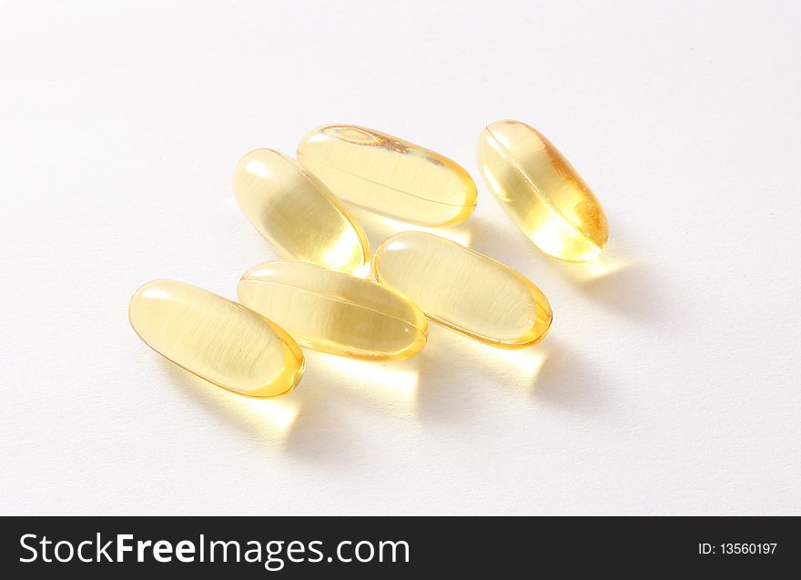 Six yellow pills on light and white background. Six yellow pills on light and white background