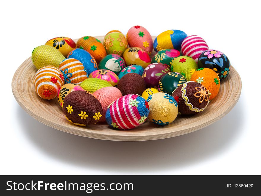Handmade easter eggs on wooden plate. Small eggs are covered by cotton string in different colours. Additional decorative elements are glued to egg. Isolated object. Handmade easter eggs on wooden plate. Small eggs are covered by cotton string in different colours. Additional decorative elements are glued to egg. Isolated object.
