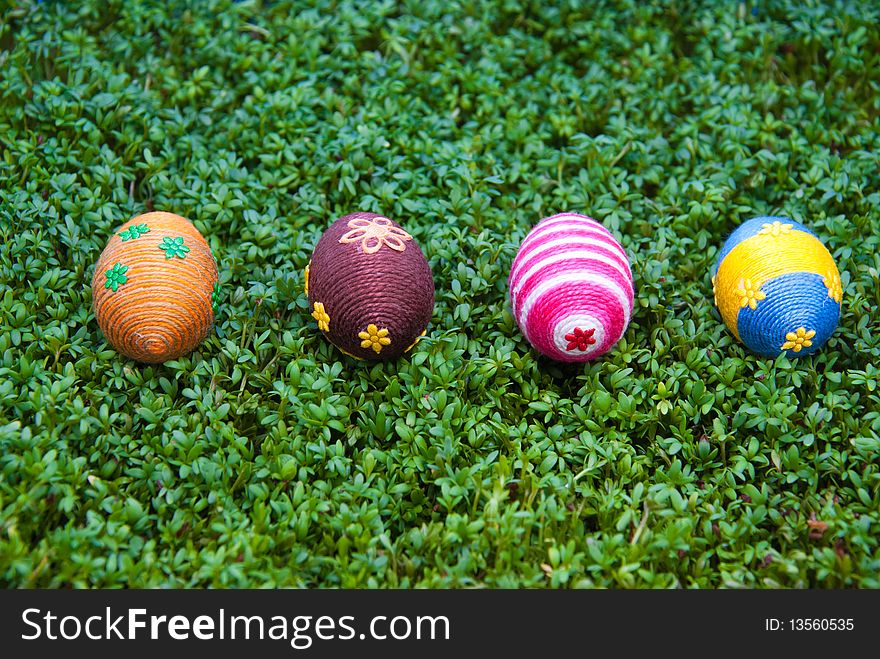 Handmade easter egg dropped on cress. Small eggs are covered by cotton string in different colours. Additional decorative elements are glued to egg. Handmade easter egg dropped on cress. Small eggs are covered by cotton string in different colours. Additional decorative elements are glued to egg.