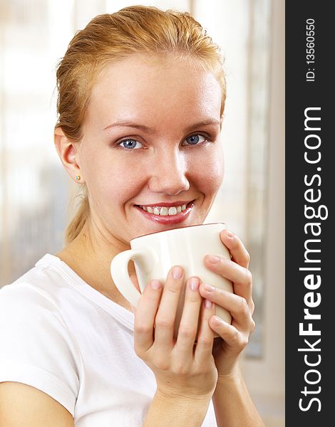 Young smiling woman with a cup at home