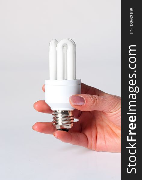 A hand holding a low energy lamp isolated against i white background. A hand holding a low energy lamp isolated against i white background