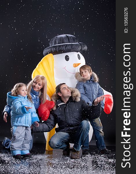 Young woman, man and children olaying near the big snow doll. Young woman, man and children olaying near the big snow doll