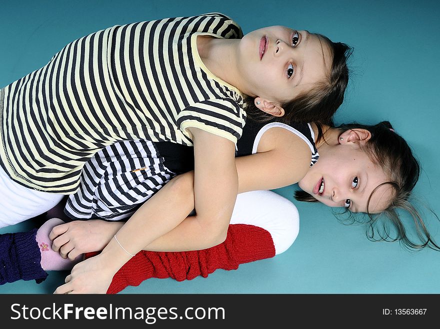 Twin white sisters exercising and practicing, turquoise background. Twin white sisters exercising and practicing, turquoise background