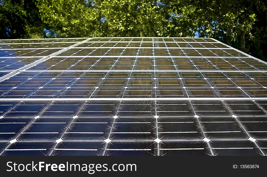 Perspective view of a solar panel with green trees on a background. Perspective view of a solar panel with green trees on a background.