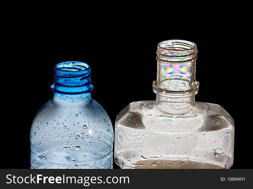 Two PET bottles in polarised light with colorful abstract patterns isolated on black. Two PET bottles in polarised light with colorful abstract patterns isolated on black