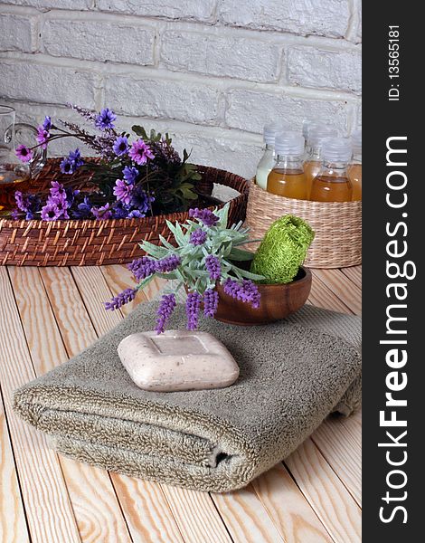 Towels,soap,fresh flowers in the wicker tray with massage oil in the wicker basket on the wooden floor. Towels,soap,fresh flowers in the wicker tray with massage oil in the wicker basket on the wooden floor.