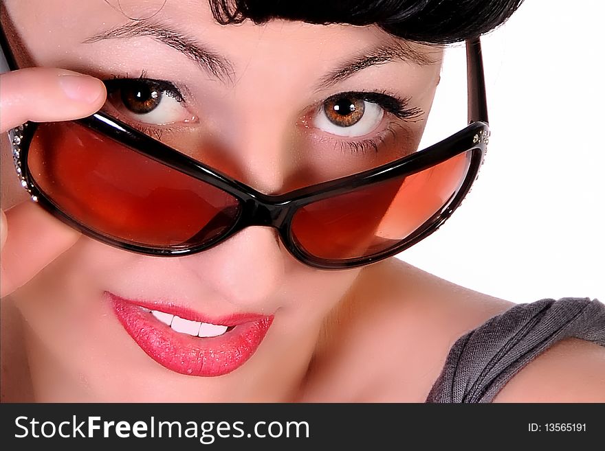 A tight close up shot of a woman with sun glasses giving a sexy look.