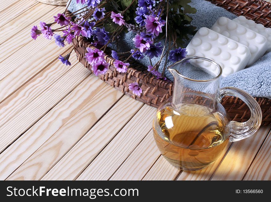 Wicker tray, towel, soaps, flowers and glass bottle on the wooden floor. Wicker tray, towel, soaps, flowers and glass bottle on the wooden floor.