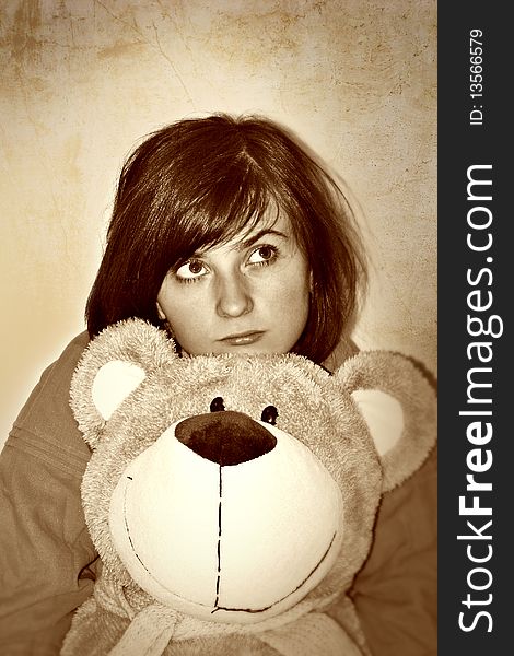 Sad girl with plush bear in hands