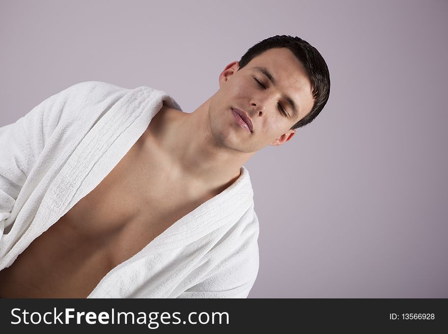 Handsome young man relaxing in the spa, wearing white towel robe. Handsome young man relaxing in the spa, wearing white towel robe.