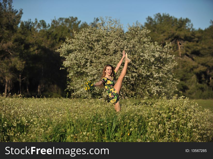 Beautiful young woman jumping in blooming meadow