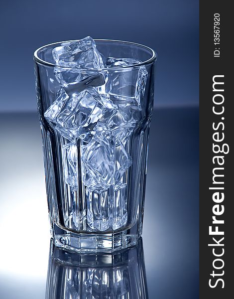 Glass of ice cubes on blue background