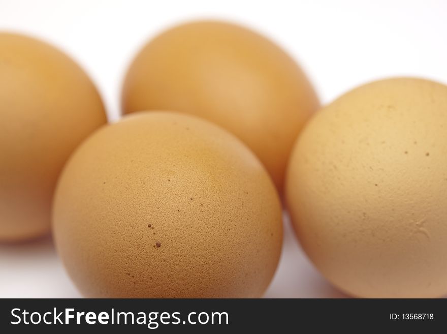 Four raw eggs on seamless white, uncracked