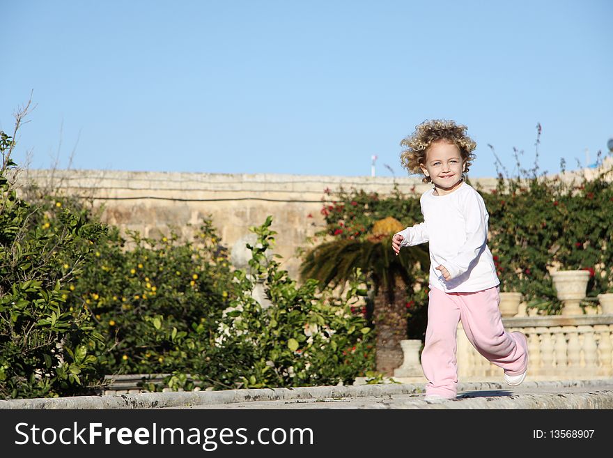 A young caucasian child with blond hair and blue eyes running happily. A young caucasian child with blond hair and blue eyes running happily