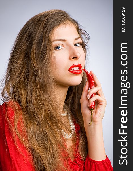 Portrait of a young beautiful girl holding her mouth red chili peppers. Portrait of a young beautiful girl holding her mouth red chili peppers