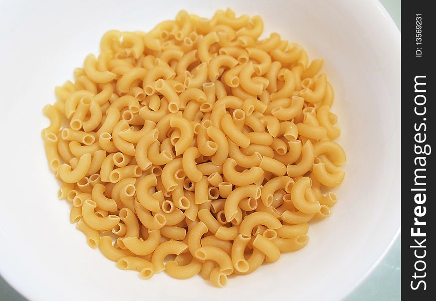 Uncooked macaroni in a white bowl