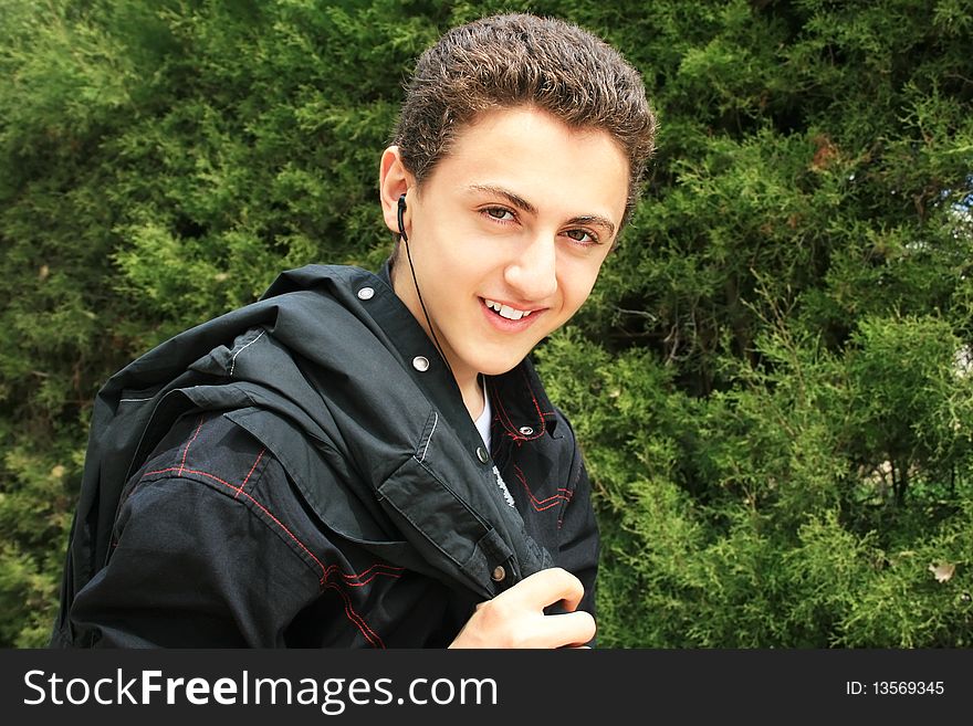 Smiling teen with ear-phones on green background.