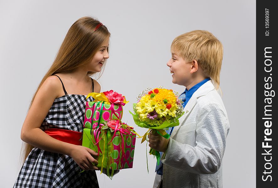Little boy with flowers in their hands gives a gift a beautiful girl. Little boy with flowers in their hands gives a gift a beautiful girl