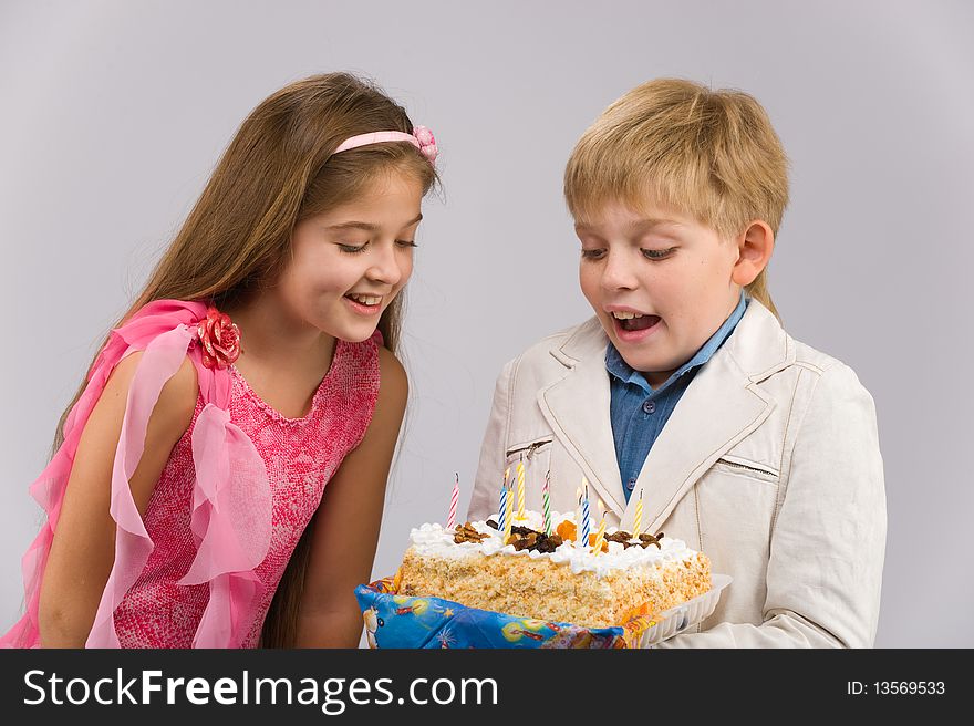 Girl in a pink dress with a cake in his hand standing next to a boy. Girl in a pink dress with a cake in his hand standing next to a boy